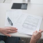 Close-up view of two individuals reviewing documents and forms in an office setting