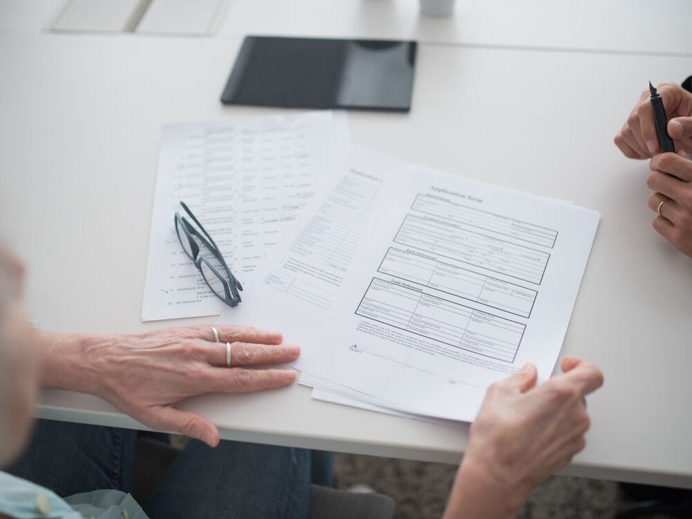 Close-up view of two individuals reviewing documents and forms in an office setting